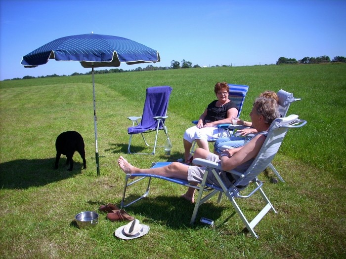 drie mensen met hond en parasol