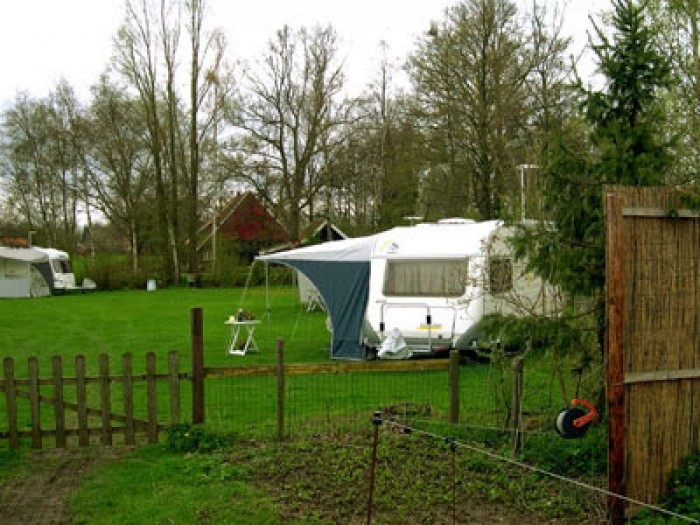 Caravan op veld met boerderij op achtergrond